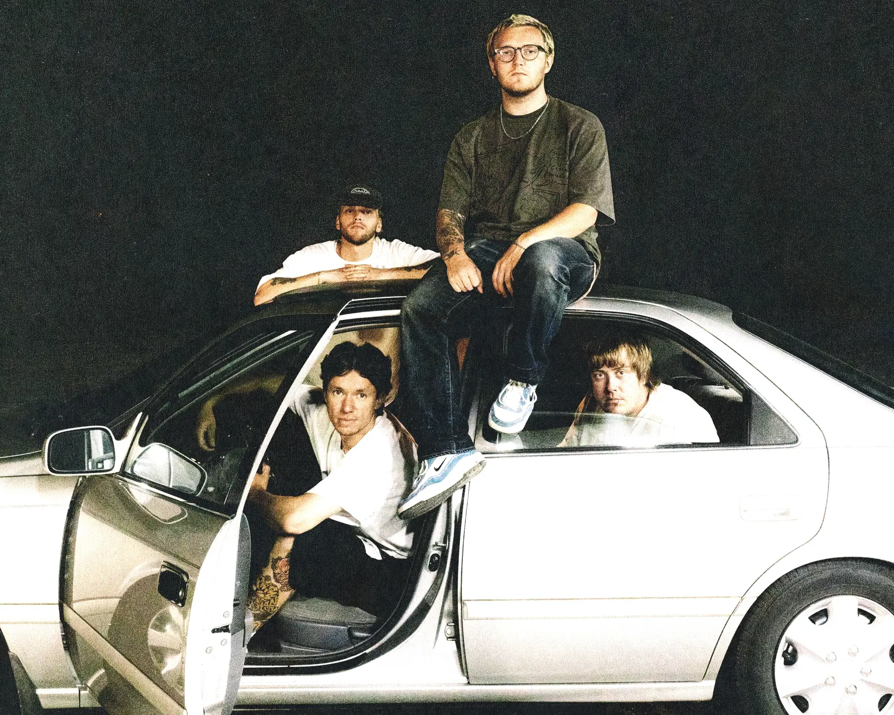 The four members of One Step Closer gathered around a silver car in an official press photo