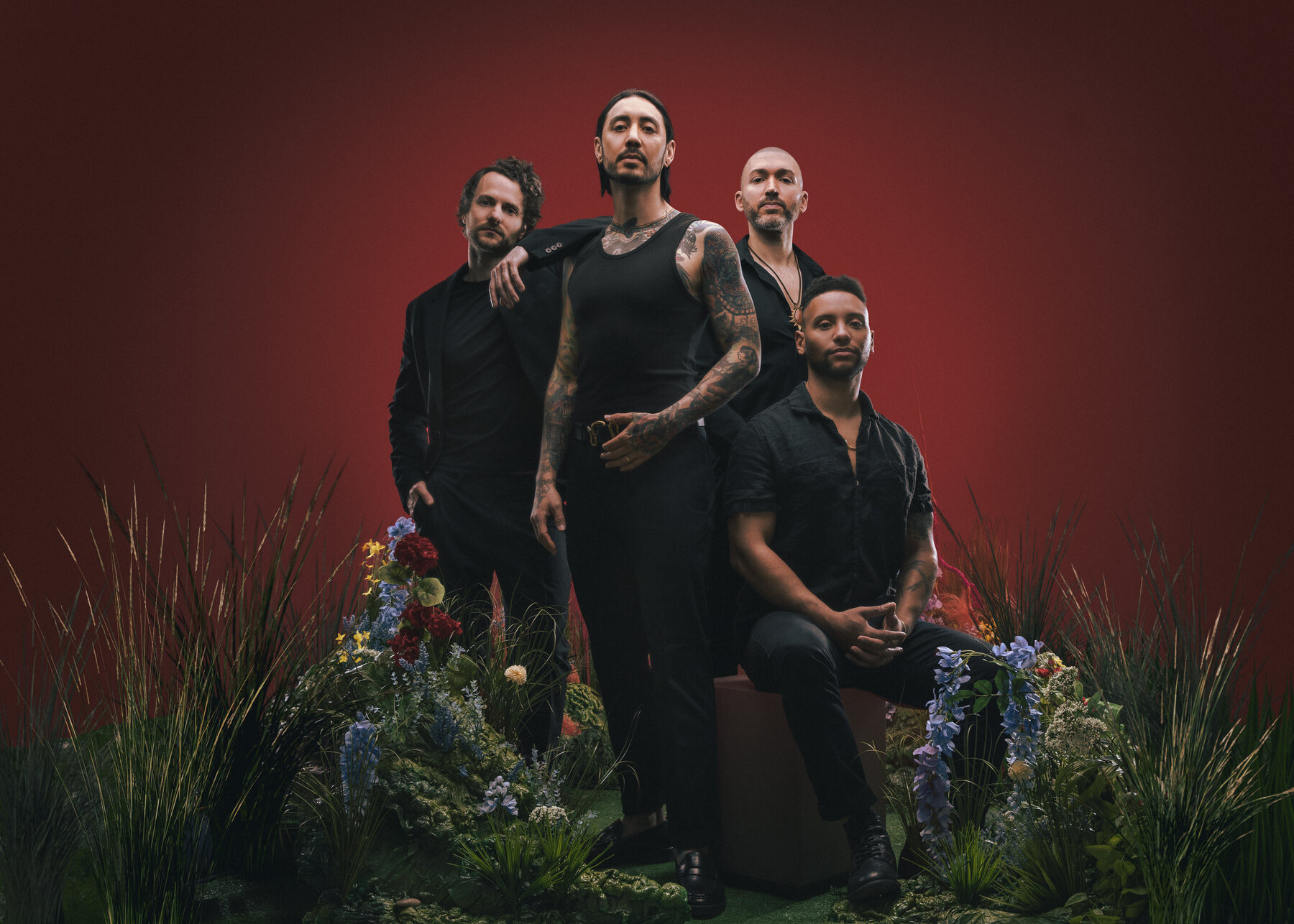 The four members of The Number Twelve Looks Like You in a red studio surrounded by flowers