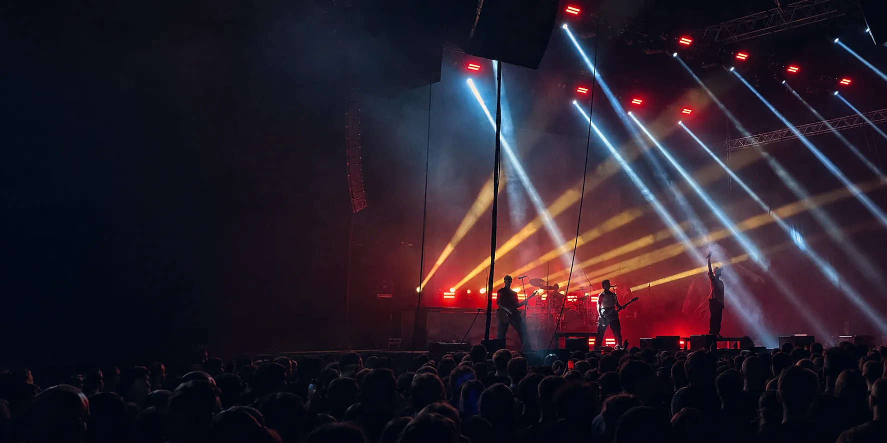 LANDMVRKS performing beneath red, gold and white stage lights in front of a festival crowd